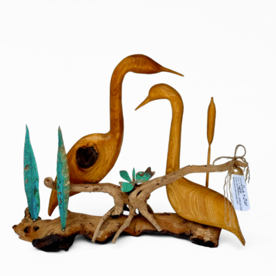 Handcrafted wooden sculpture featuring two elegant birds, possibly ducks or geese, perched on natural driftwood with teal metallic leaves and a dragonfly. This unique art piece captures wildlife.