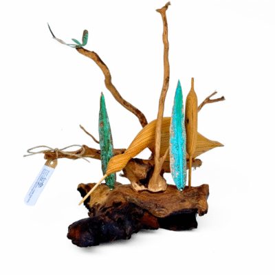 Nature-inspired driftwood sculpture with a long-beaked carved bird, vibrant teal foliage, and a small dragonfly resting on gnarled wood branches.